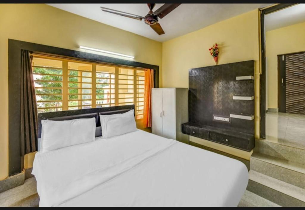 a bedroom with a large white bed and a television at Goroomgo Moon CT Road Puri - 100 Meter From Sea Beach - Best Choice of Travelers in Puri
