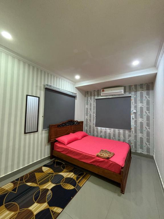 a bedroom with a red bed in a room at Embun Selasih Homestay in Pasir Gudang
