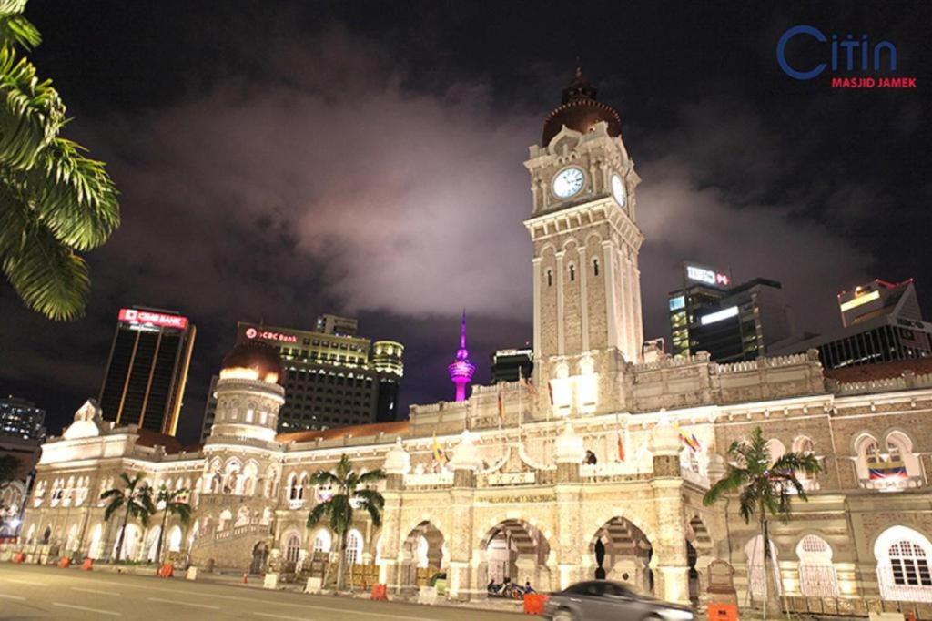 un grand bâtiment avec une tour d'horloge la nuit dans l'établissement Citin Hotel Masjid Jamek by Compass Hospitality, à Kuala Lumpur