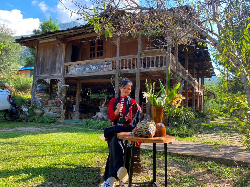 una mujer sentada en una mesa frente a una casa en Ngoc Chien Pearl, 