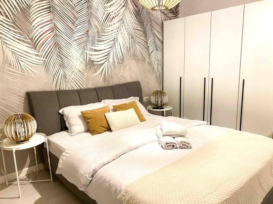 Un dormitorio con una gran cama blanca con almohadas amarillas. en Serene Ambiance Amazing 1BR with private parking, en Voluntari