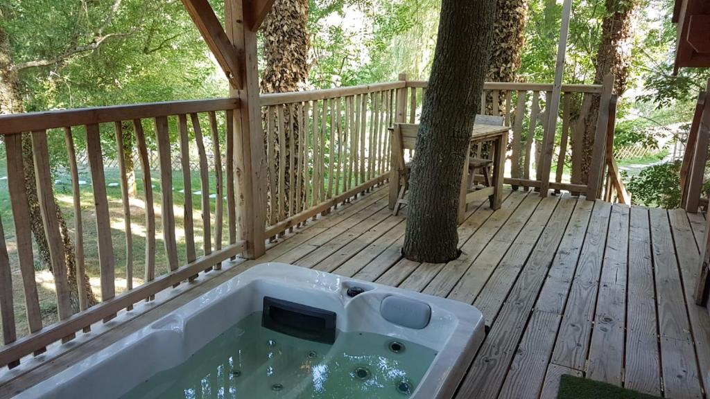 a hot tub on a deck with a tree at Cabane perchée luxe avec jacuzzi Domaine du Marais Maisse in Maisse