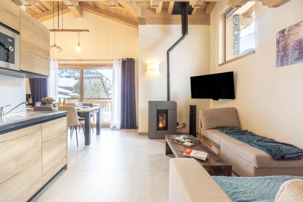 eine Küche und ein Wohnzimmer mit einem Sofa und einem Kamin in der Unterkunft Chalet la Parrachée in Lanslebourg-Mont-Cenis