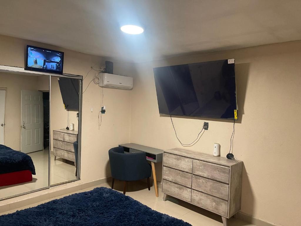 1 dormitorio con escritorio y TV en la pared en La casa de Mickey, en Ciudad Juárez