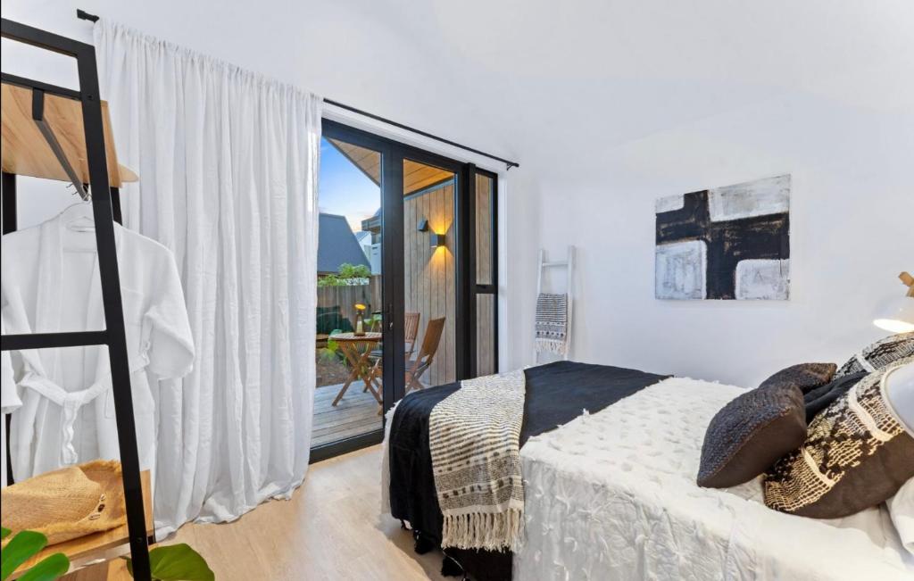 a bedroom with a bed and a sliding glass door at Matakana Luxury Escapes in Matakana