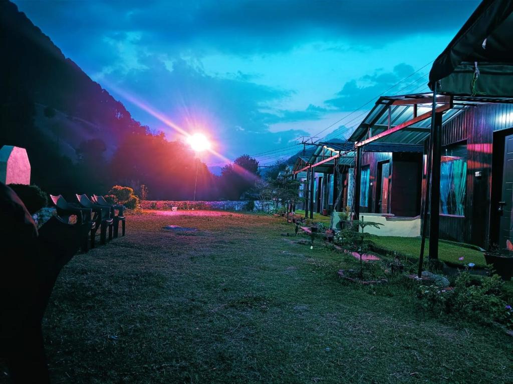 a building with the sun setting in the background at Jayara Resort And Cafe in Barkot