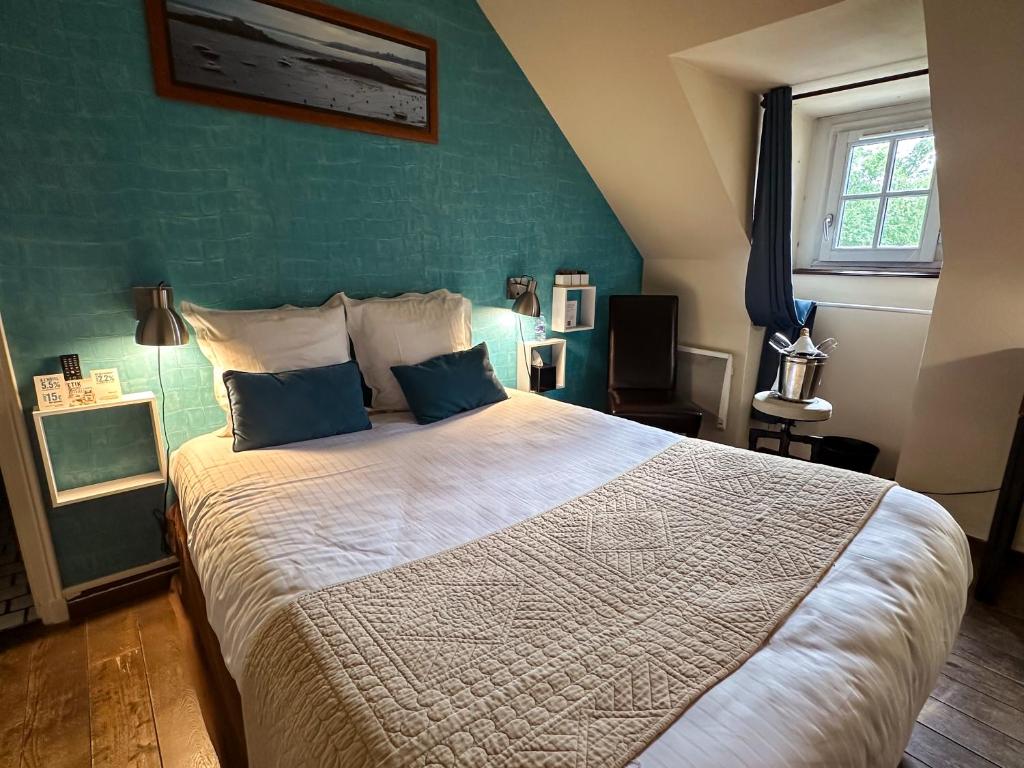 a bedroom with a large bed with a green wall at Logis Hôtel Le Manoir Des Portes in Lamballe