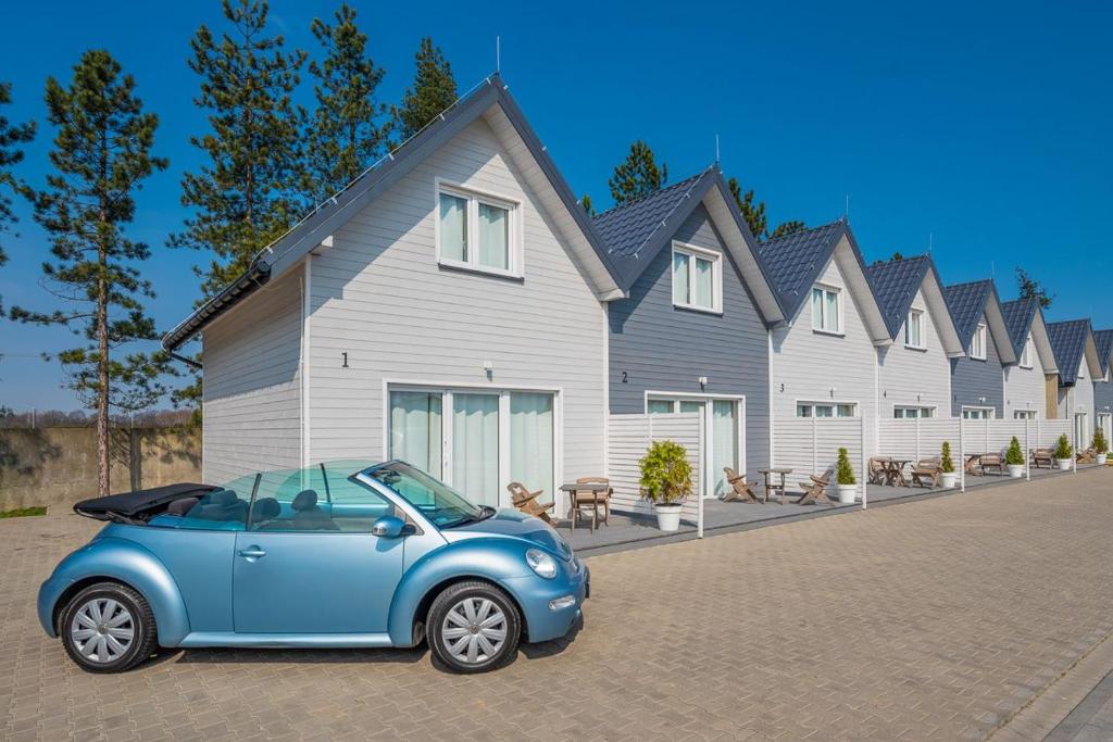 een kleine blauwe auto geparkeerd voor een huis bij Old Tree Village & Restaurant in Oświęcim