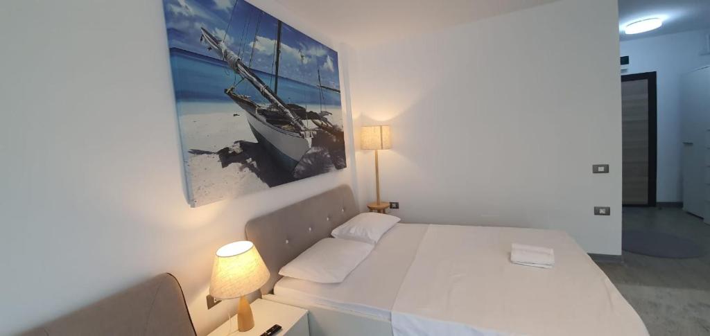 a white bedroom with a bed and a picture on the wall at Alezzi Luxury Family Studio & Spa Piscina Acoperita Incalzita,Sauna uscata si umeda,Jacuzzi in Mamaia Sat/Năvodari