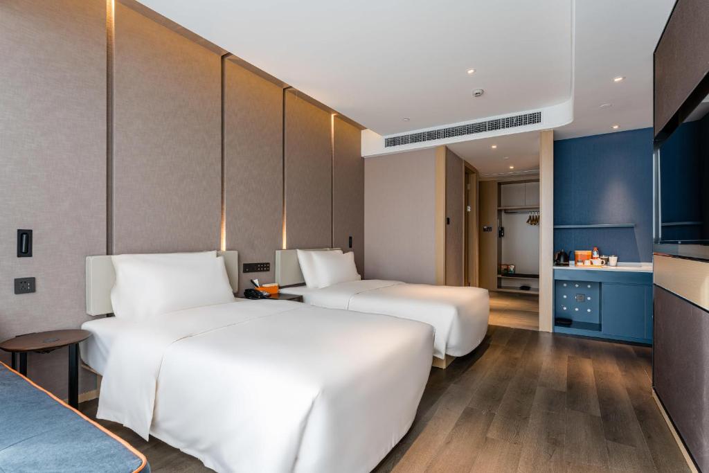 two beds in a hotel room with a kitchen at Atour Hotel Shaoxing Jinghu City Hall Basketball Theme in Shaoxing