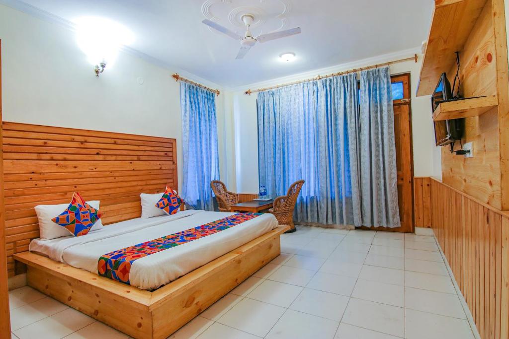 1 dormitorio con 1 cama grande y TV. en FabHotel Greenwoods Inn, en Dharamshala