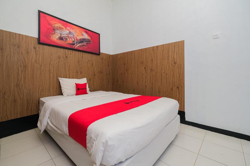 een slaapkamer met een groot wit bed en een rode deken bij RedDoorz Syariah near RSUD Tuban in Tuban