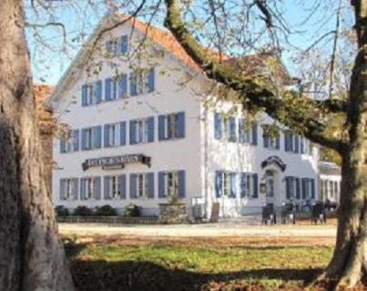 ein großes weißes Gebäude mit blauen Fenstern in einem Park in der Unterkunft Deutsches Haus in Waal