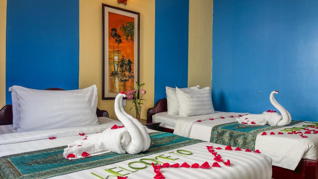 ein Hotelzimmer mit 2 Betten mit Schwänen darauf in der Unterkunft Harmony Indochine d'Angkor in Siem Reap