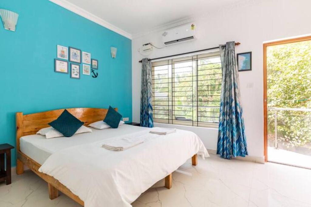 a bedroom with a bed with blue walls and a window at Cerca Del Mar in Calangute
