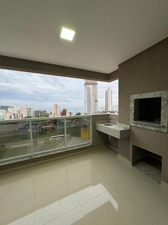 een kamer met een groot raam met uitzicht op de stad bij Apartamento à 390m do Mar in Itapema