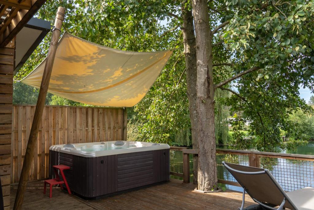 eine Hängematte, die über einem Whirlpool auf einer Terrasse hängt in der Unterkunft Camping du Château Vert in Hondainville