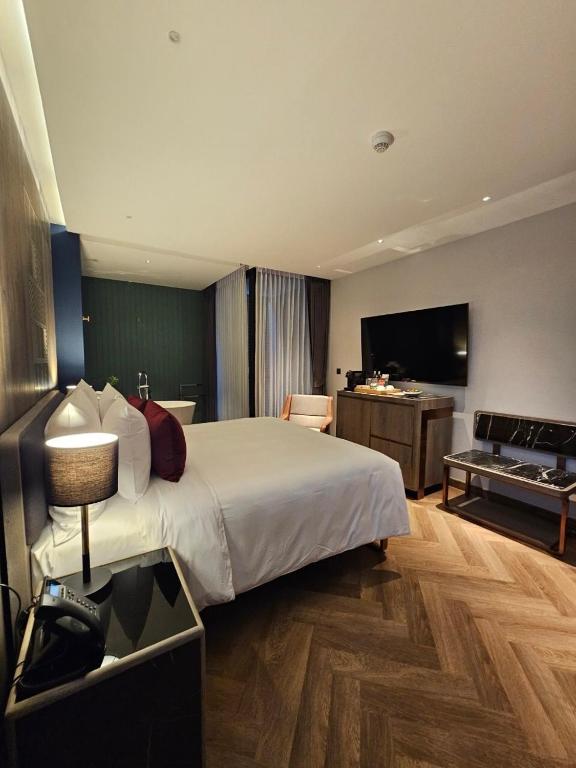 A tall bedroom view showing the full bed, television wall and lounge chair.