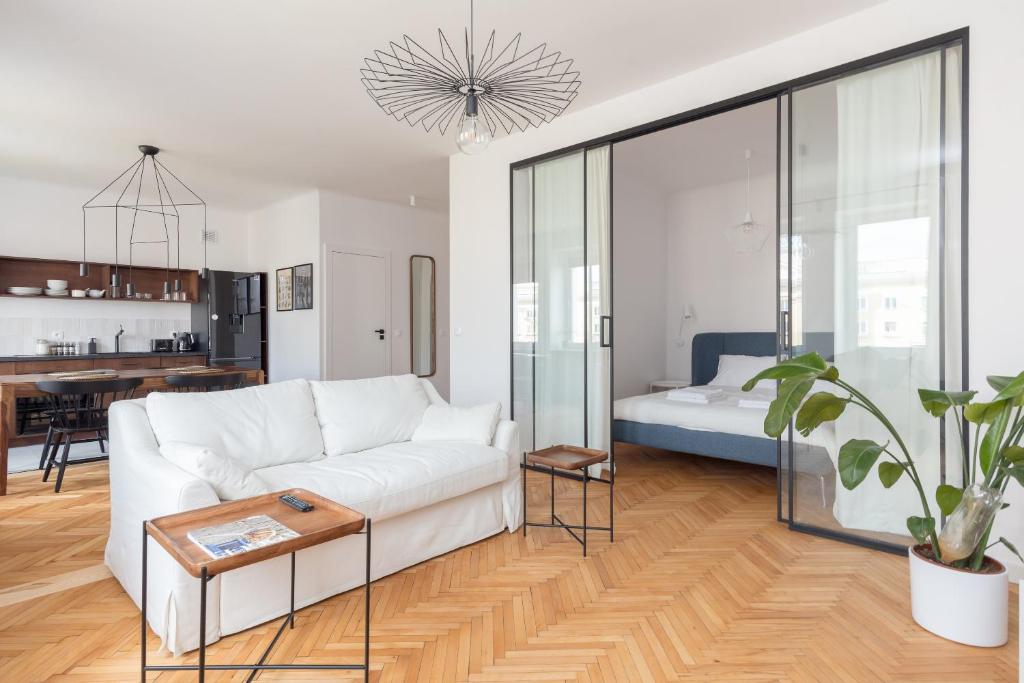 een woonkamer met een witte bank en een tafel bij Designer Apartment in the Central Warsaw in Warschau
