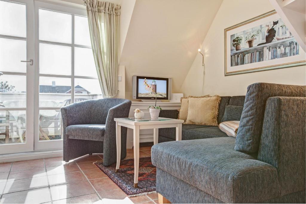 ein Wohnzimmer mit einer Couch und zwei Stühlen und einem Tisch in der Unterkunft Friesenhörn, App. 4 links in Wenningstedt-Braderup