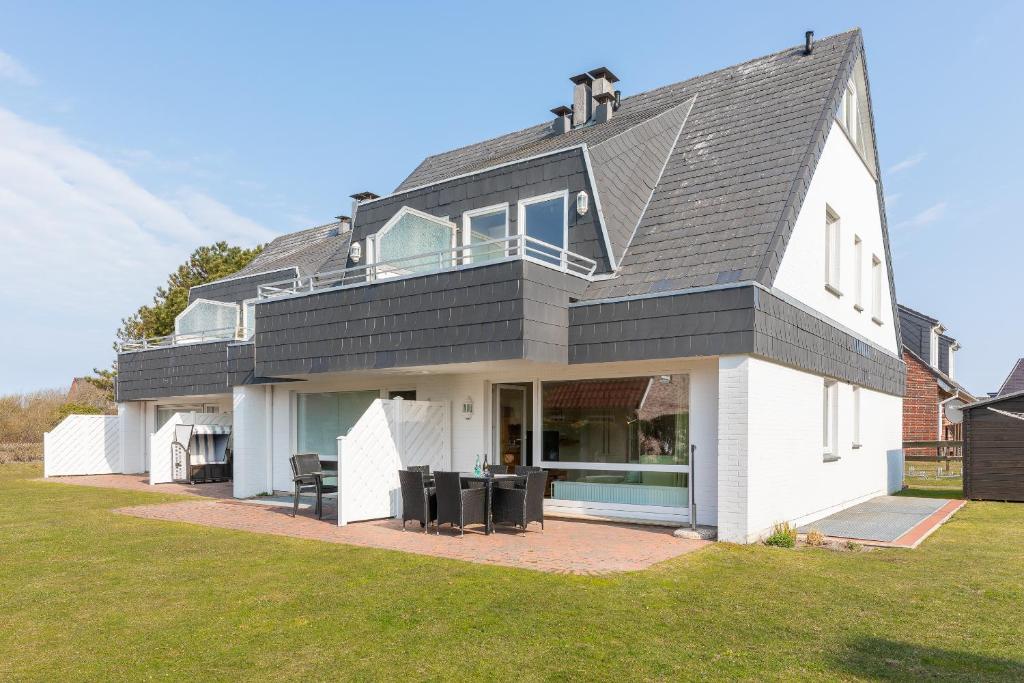 ein großes weißes Haus mit schwarzem Dach in der Unterkunft Haus Sonnenschein, Whg. H in Wenningstedt-Braderup
