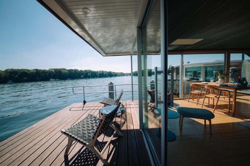 a boat deck with chairs and a table on the water at JULIA - Schwimmendes Apartment in Berlin
