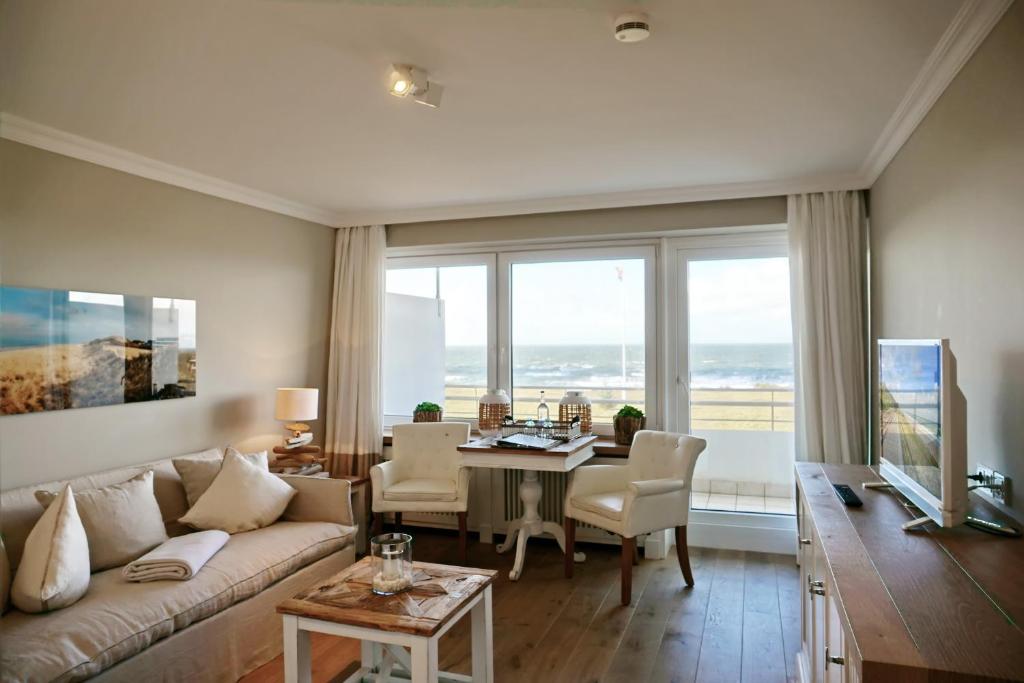 uma sala de estar com um sofá e uma mesa em Seafront Duenenhof zum Kronprinzen em Wenningstedt