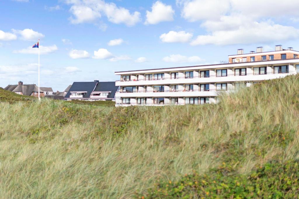 un bâtiment au sommet d'une colline herbeuse avec drapeau dans l'établissement Milla App 4, à Wenningstedt