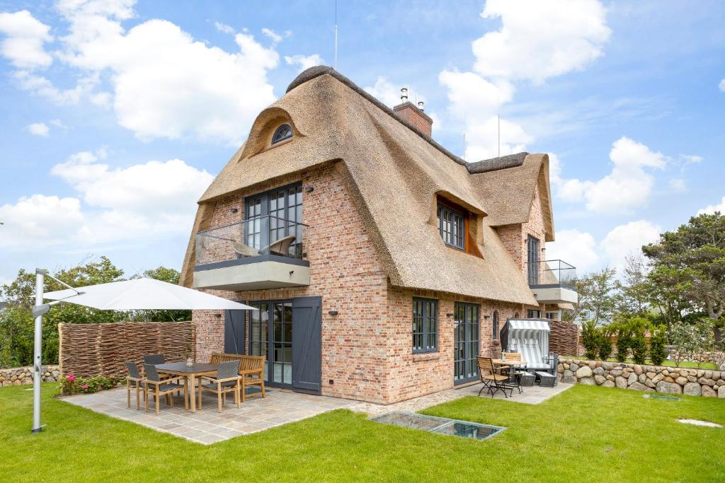 a thatch roofed house with a table in the yard at Fien to Huus in Wenningstedt