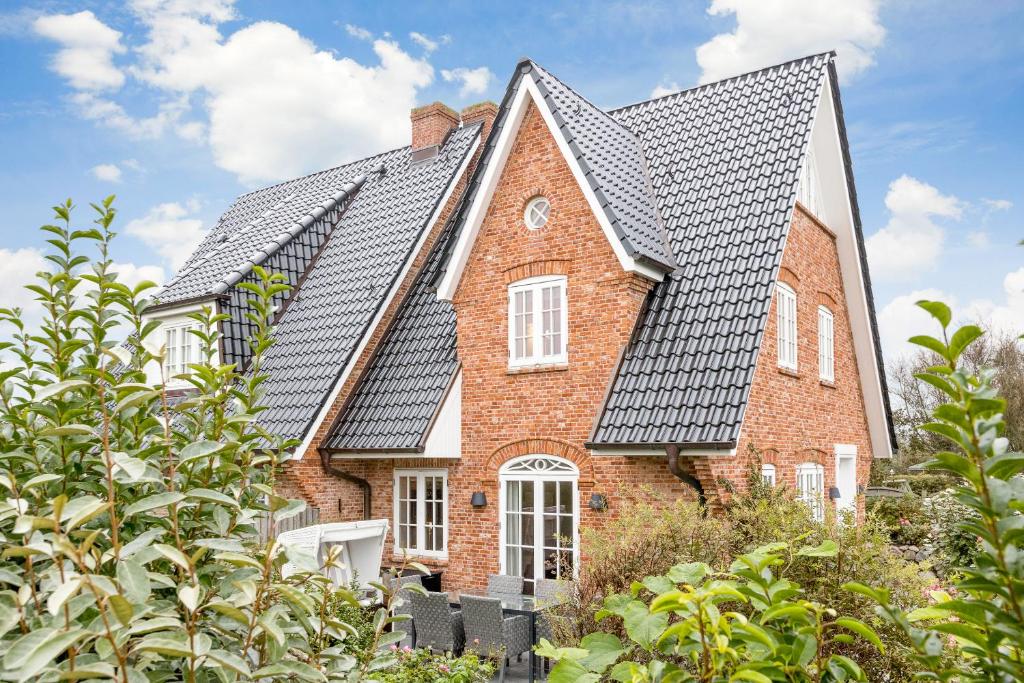 ein rotes Backsteinhaus mit einem schwarzen Dach in der Unterkunft Haus Seaside in Wenningstedt-Braderup
