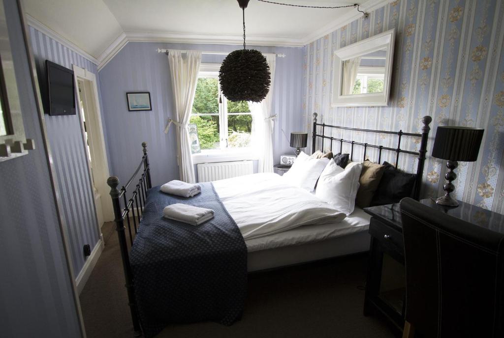 a bedroom with a bed with white sheets and a window at Torpet Mon in Gothenburg