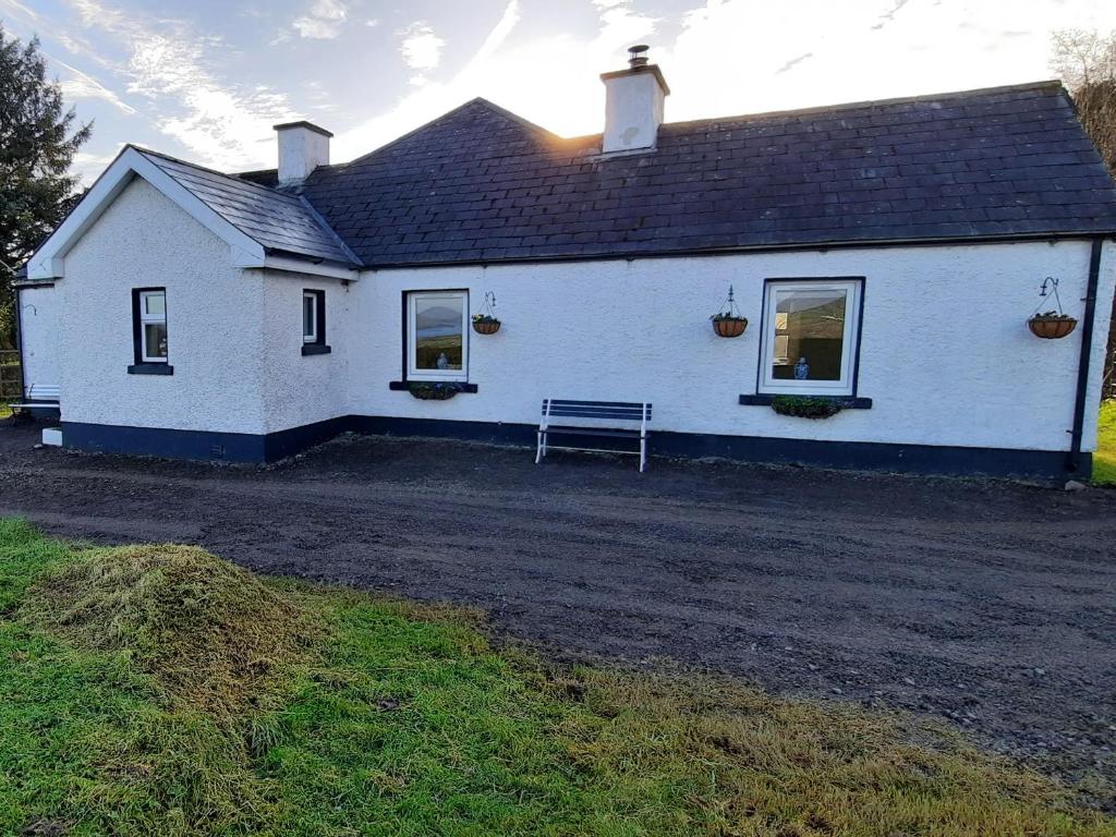 a white house with a bench in front of it at Ballaghboy Cottage in Boyle