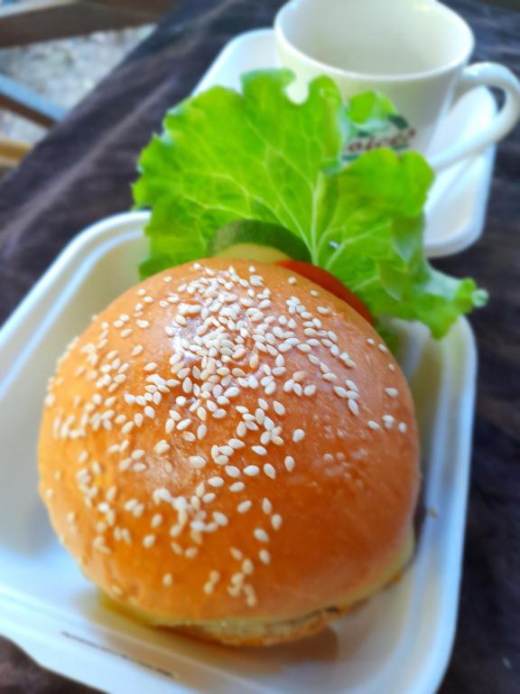 einen Sesamburger auf einem weißen Teller mit einer Tasse in der Unterkunft Neena S Hostel in Ban Nua