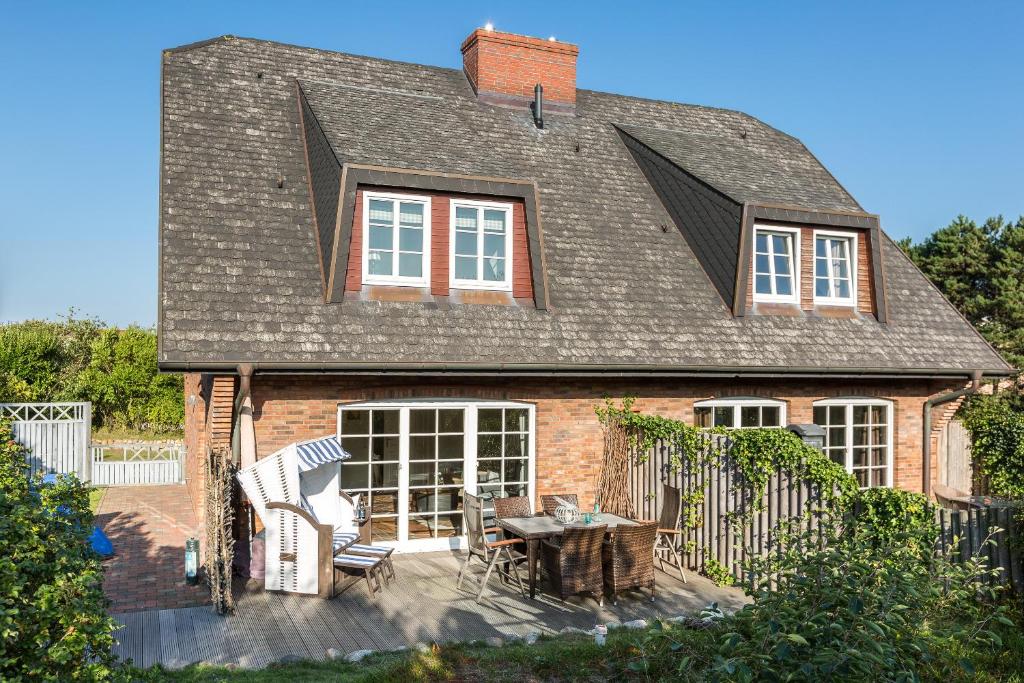 a brick house with a table and chairs on a patio at Heide Hues in Munkmarsch