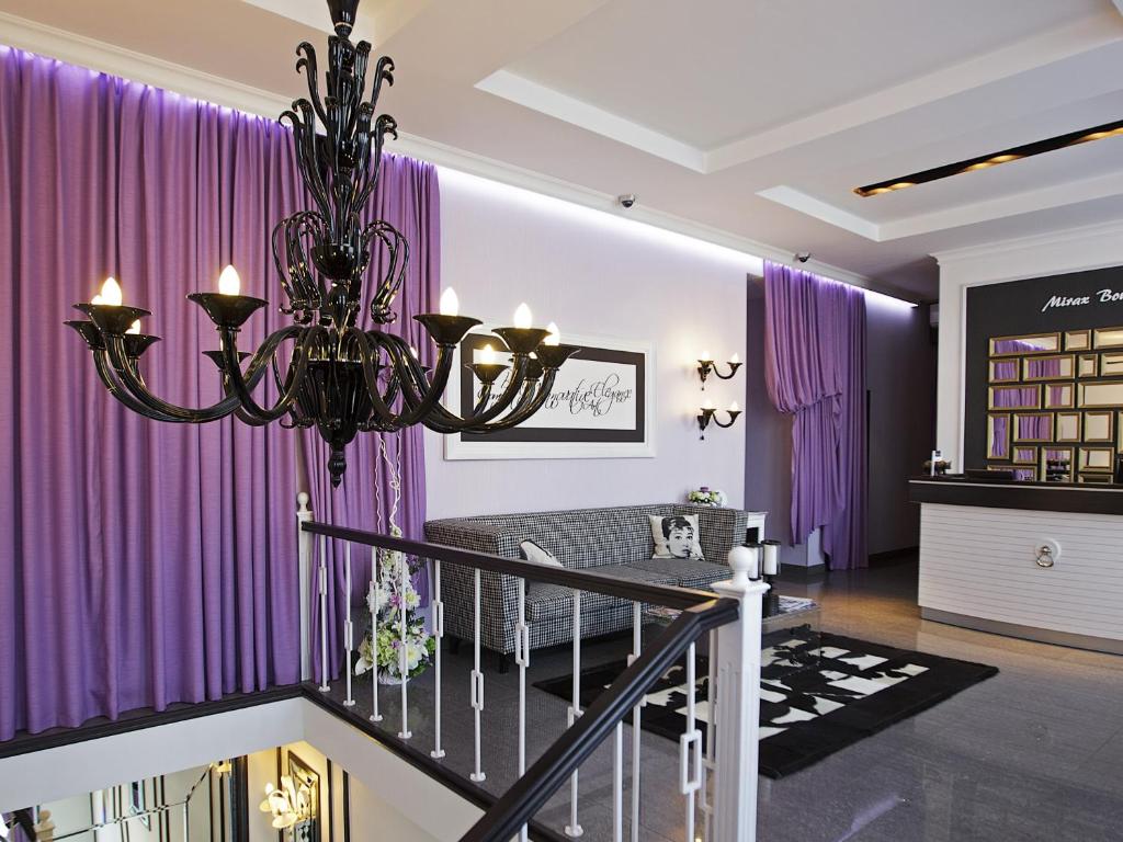 Habitación con cortinas moradas y lámpara de araña. en Mirax Boutique Hotel en Járkov