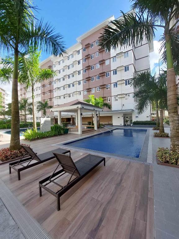 a hotel with a swimming pool and palm trees at Sojourn at SMDC Hope Residences in Trece Martires