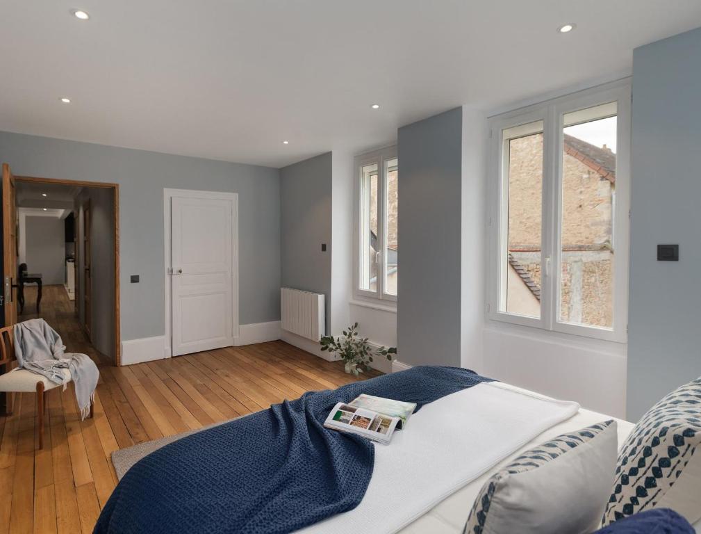 a bedroom with a bed and two windows at Maison Lùisa in Autun