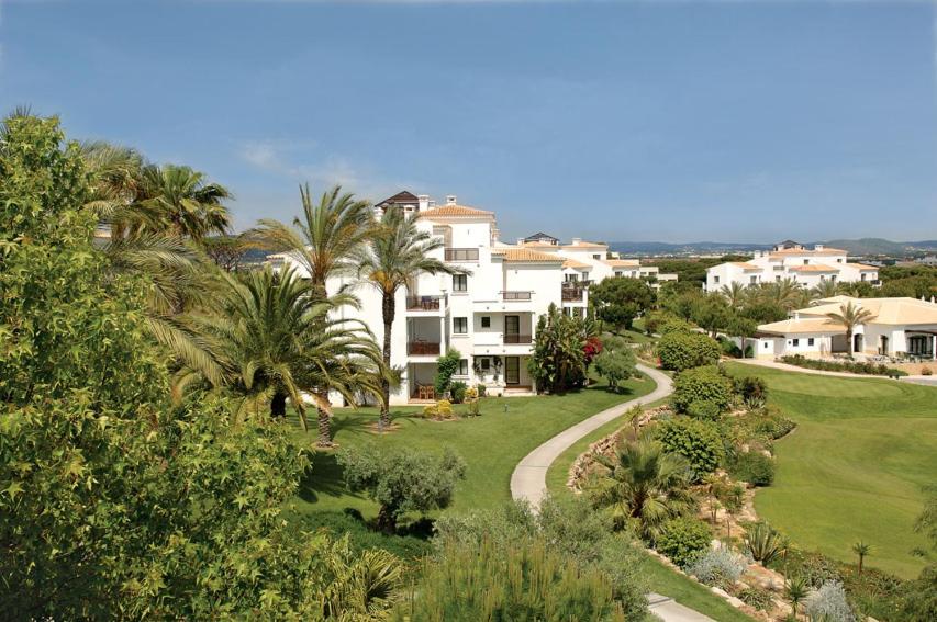 a view of a resort with palm trees and a road at Pine Cliffs Suites in Albufeira