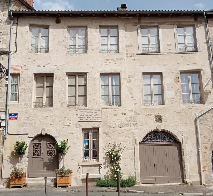 un vecchio edificio in pietra con due porte e finestre di Maison gay lussac a Saint-Léonard-de-Noblat