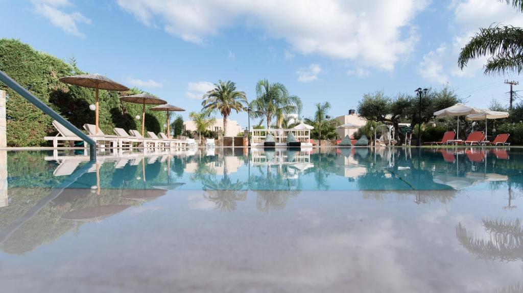 a large swimming pool with chairs and umbrellas at Mirage Studios in Malia