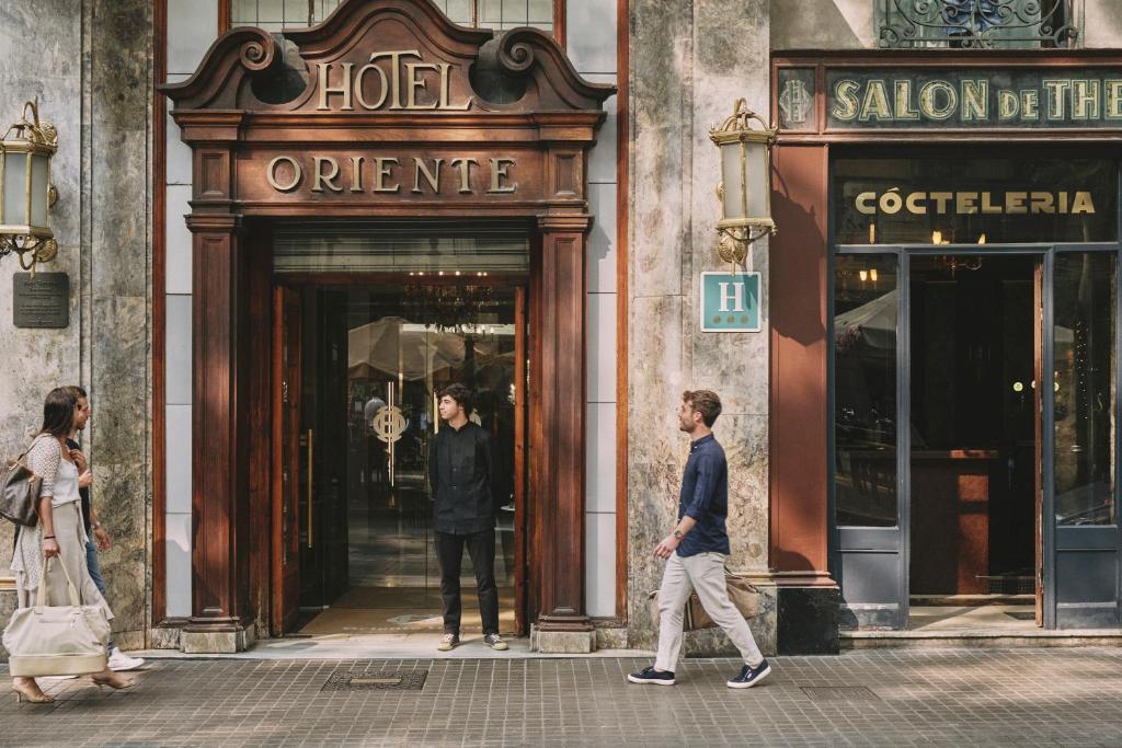 dos personas caminando en frente de una tienda en Oriente Atiram, en Barcelona