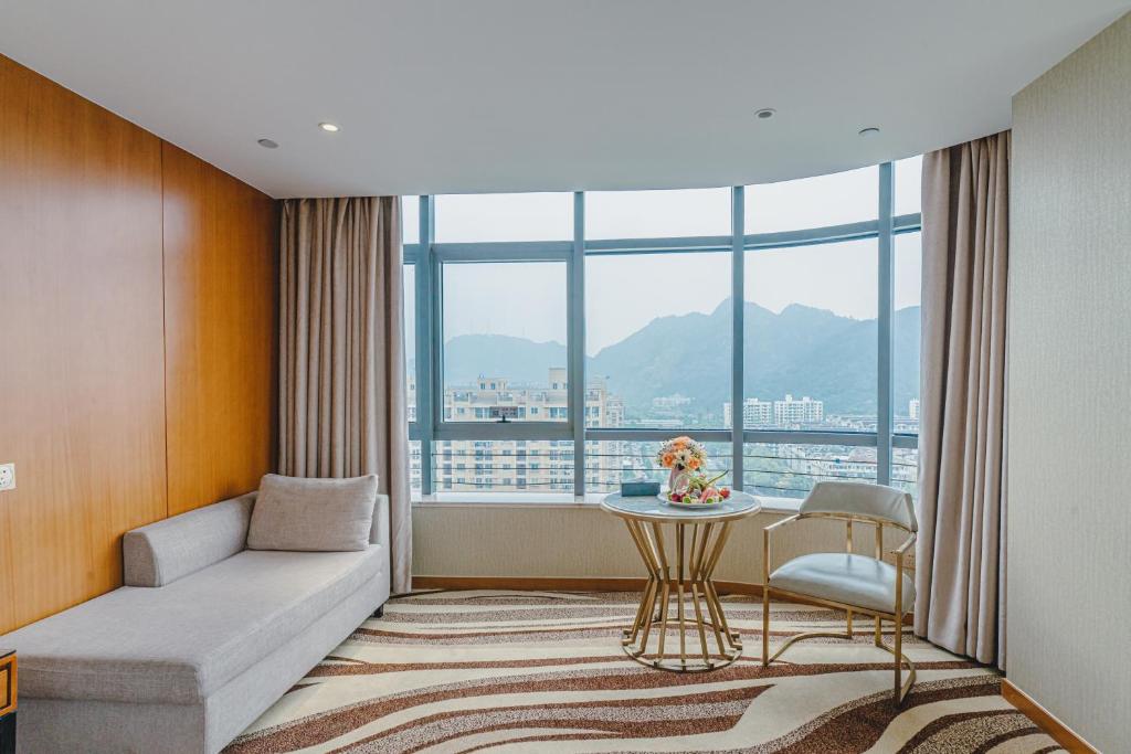 温州市にあるWenzhou Hangbin International Hotelのソファ、テーブル、窓が備わる客室です。