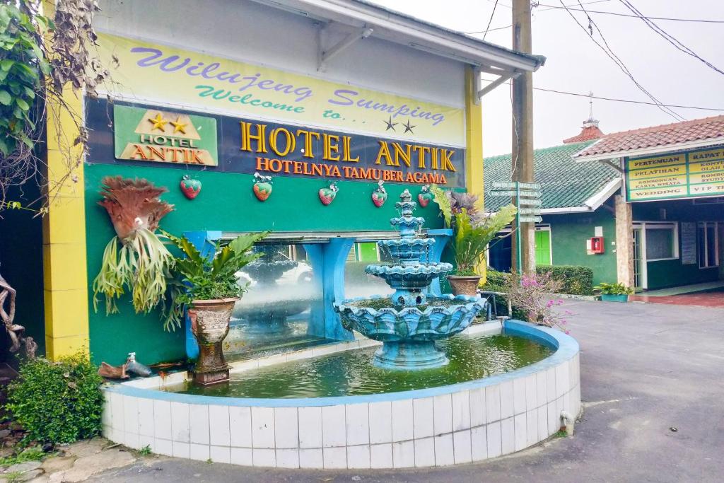 a hotel entrance with a fountain in front of a building at Hotel Antik in Soreang