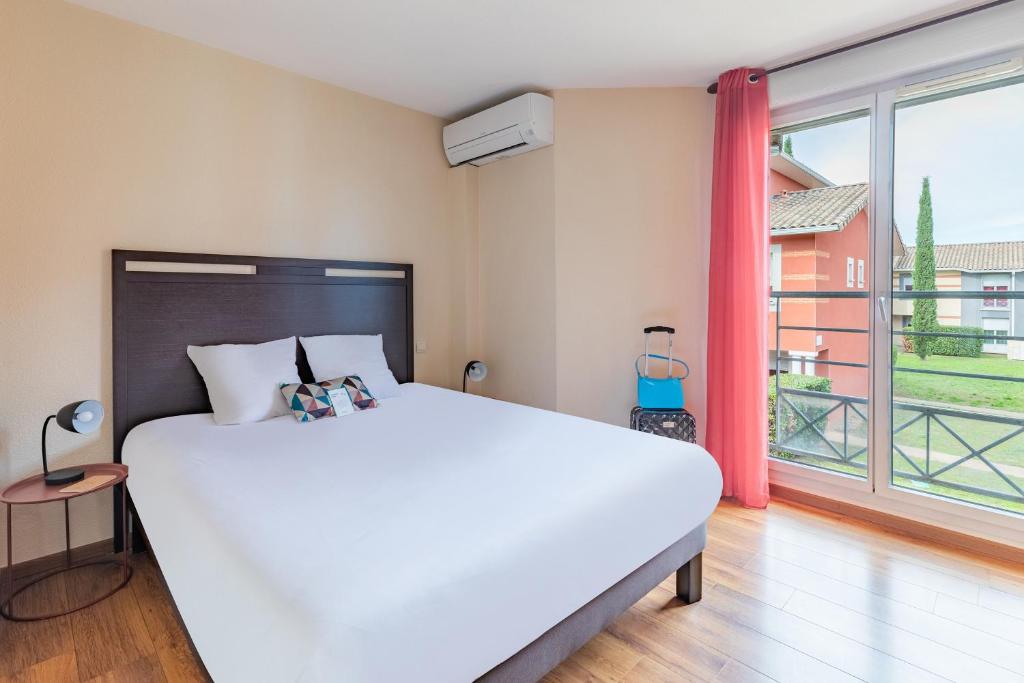 トゥールーズにあるAppart'City Classic Toulouse Saint-Simonのベッドルーム(大きな白いベッド1台、大きな窓付)