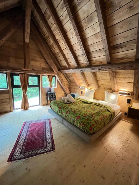 - une chambre avec un grand lit dans une pièce dotée de plafonds en bois dans l'établissement Le Grand Petit Prince - Domaine de Charme - Jacuzzis privatifs, à Guebwiller