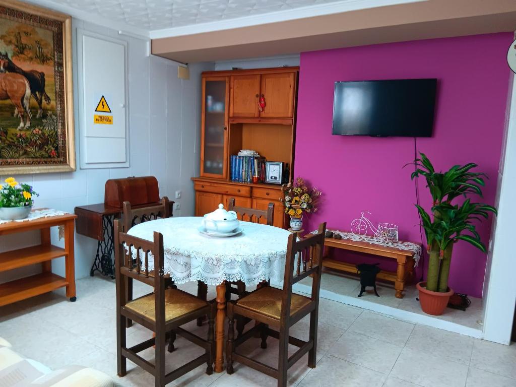 a dining room with a table and a pink wall at La Replaceta in Chulilla