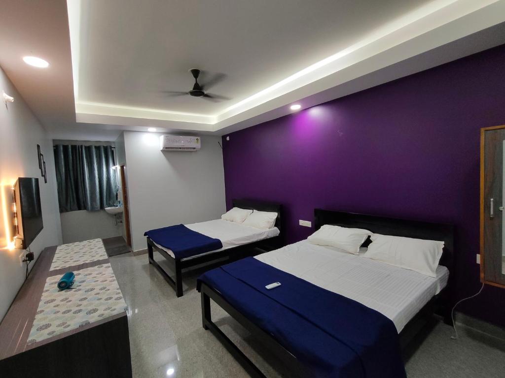 two beds in a room with a purple wall at Sadafuli Guest House Assagao in Assagao