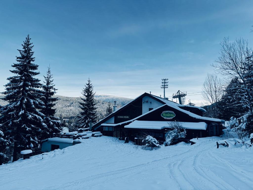 um celeiro coberto de neve com árvores e uma estrada em Myslivna Harrachov em Harrachov