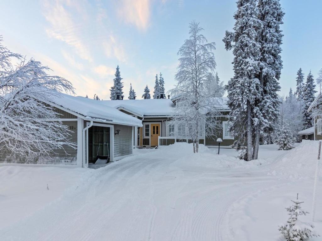 a house covered in snow with trees and a driveway at Holiday Home Rukan taikavuosseli 12 a by Interhome in Ruka