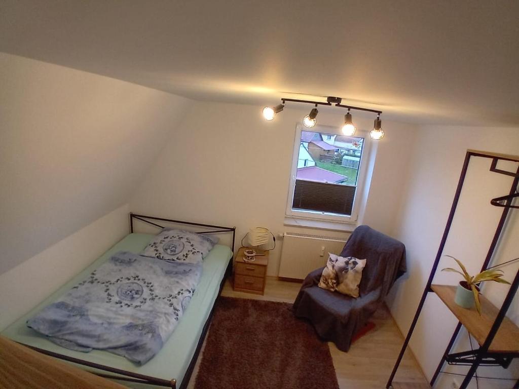 ein Schlafzimmer mit einem Bett, einem Stuhl und einem Fenster in der Unterkunft Ferienwohnung Rössewiese in Schleusingen